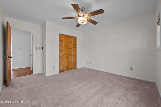 unfurnished bedroom featuring ceiling fan, a closet, and light colored carpet