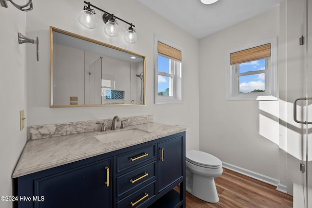 bathroom with hardwood / wood-style flooring, vanity, toilet, and an enclosed shower