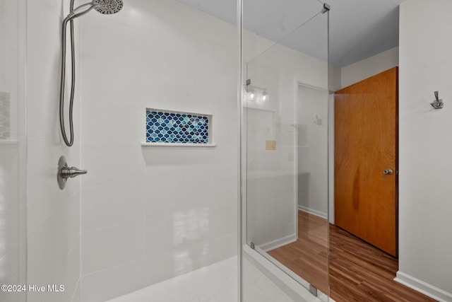 bathroom with hardwood / wood-style floors and a tile shower