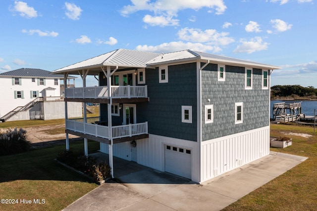 rear view of house featuring a lawn, a balcony, a water view, and a garage