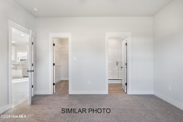 unfurnished bedroom featuring a spacious closet, light carpet, and a closet