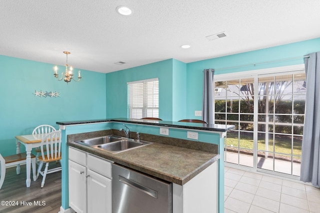 kitchen with dishwasher, an inviting chandelier, white cabinets, a center island with sink, and sink