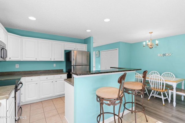 kitchen featuring pendant lighting, a kitchen island, white cabinetry, and stainless steel appliances