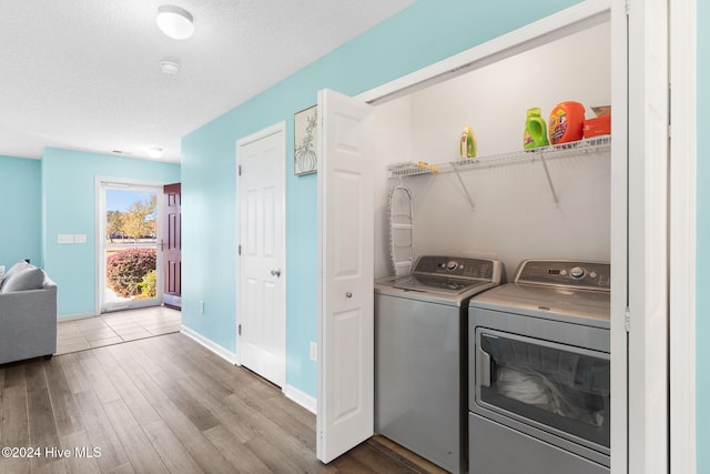 clothes washing area featuring light hardwood / wood-style floors, independent washer and dryer, and a textured ceiling