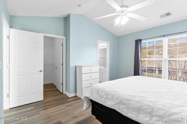 bedroom with ensuite bath, ceiling fan, vaulted ceiling, a closet, and hardwood / wood-style flooring