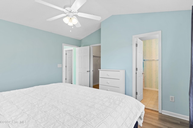 bedroom with ensuite bathroom, vaulted ceiling, ceiling fan, wood-type flooring, and a closet