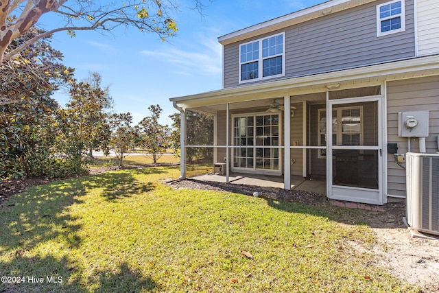 rear view of property with a sunroom, cooling unit, and a lawn