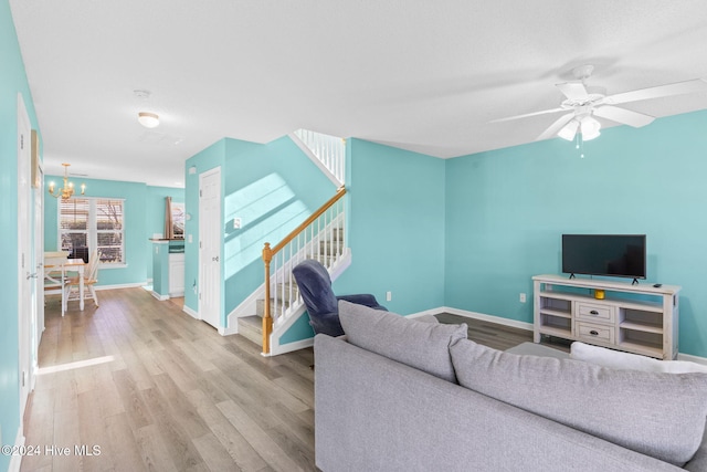 living room featuring light hardwood / wood-style floors and ceiling fan with notable chandelier