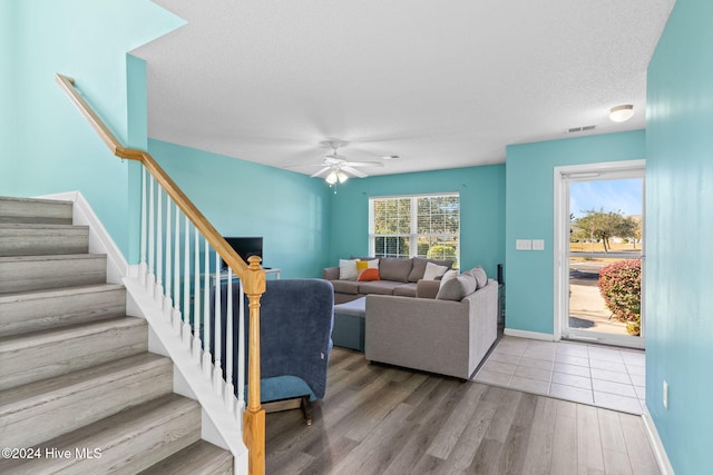 living room featuring ceiling fan, a textured ceiling, and hardwood / wood-style flooring