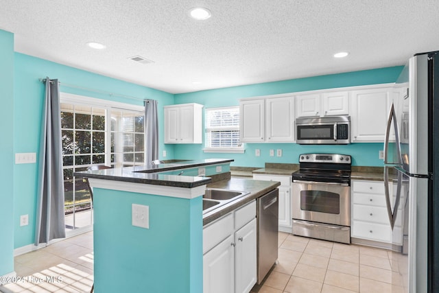 kitchen featuring white cabinets, a healthy amount of sunlight, a kitchen island, and stainless steel appliances