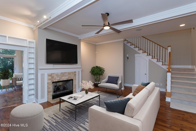 living room featuring a tile fireplace, dark hardwood / wood-style floors, ceiling fan, built in shelves, and ornamental molding