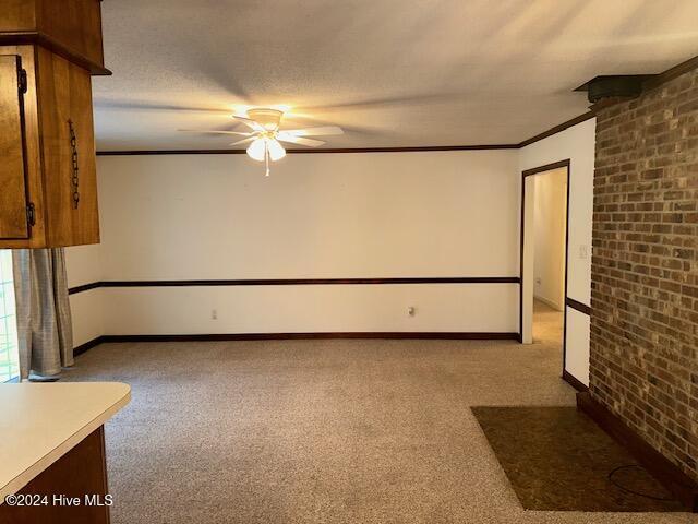 1738 NC-306 Hwy S, Grantsboro, NC 28529 - carpeted empty room featuring ceiling fan, baseboards, brick wall, and ornamental molding
