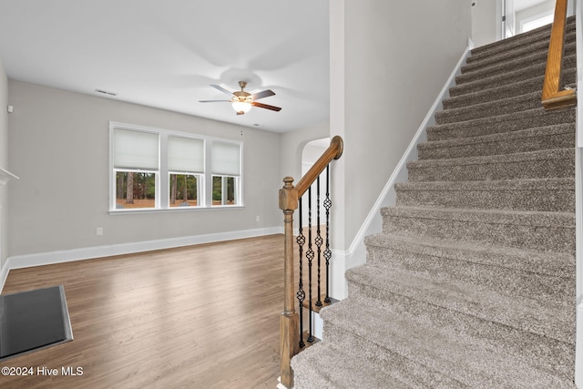 stairs featuring hardwood / wood-style floors and ceiling fan