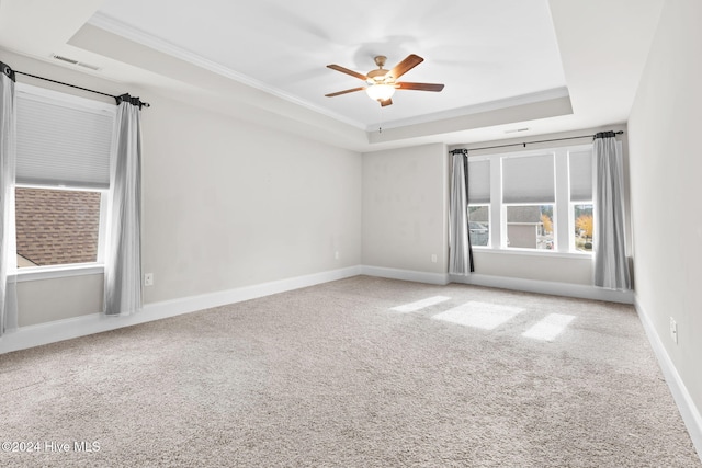 carpeted spare room featuring a raised ceiling, ceiling fan, and crown molding