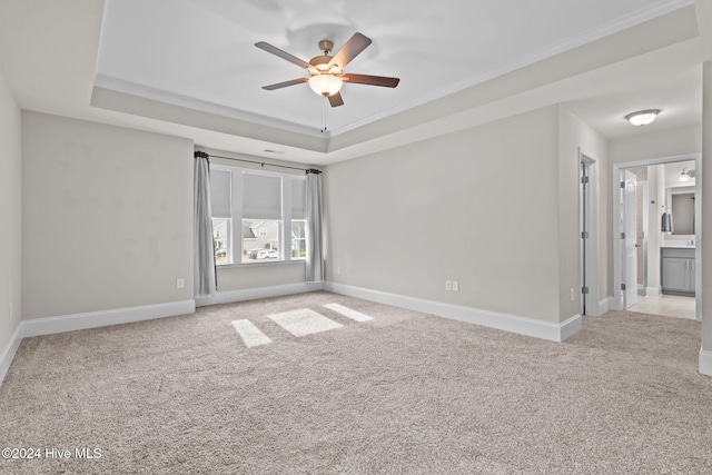 carpeted empty room with a tray ceiling, ceiling fan, and ornamental molding