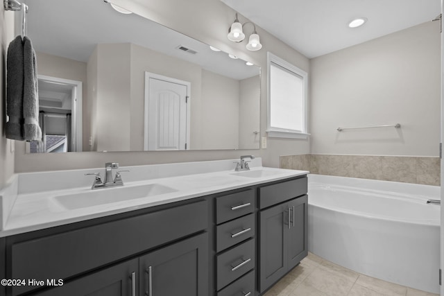 bathroom with a washtub, vanity, and tile patterned flooring