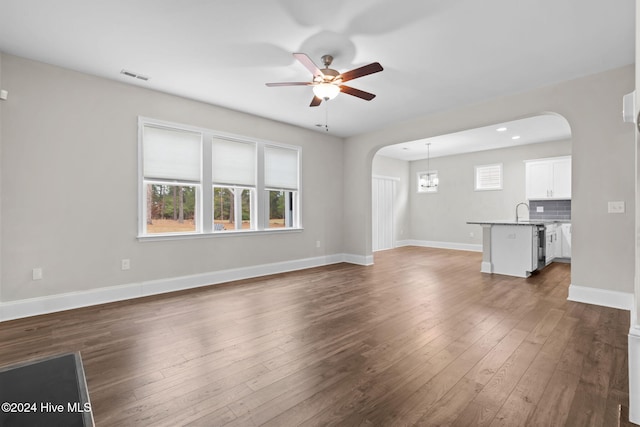 unfurnished living room featuring dark hardwood / wood-style floors, sink, and ceiling fan with notable chandelier