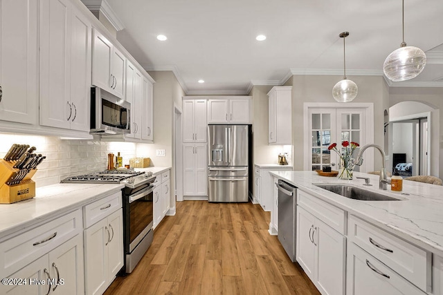 kitchen with white cabinets, sink, hanging light fixtures, light hardwood / wood-style flooring, and stainless steel appliances