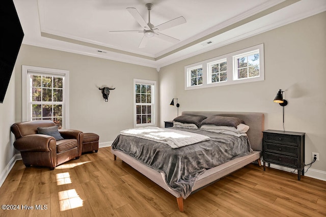 bedroom featuring a tray ceiling, ceiling fan, light hardwood / wood-style flooring, and crown molding