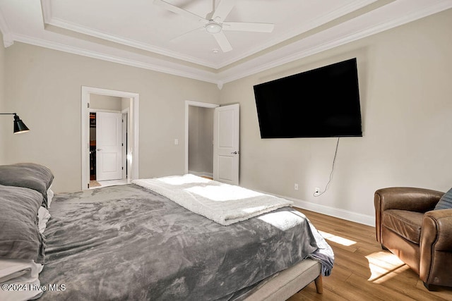 bedroom featuring wood-type flooring, a tray ceiling, ceiling fan, and crown molding