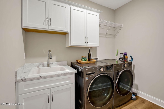 laundry room with separate washer and dryer, sink, cabinets, and light wood-type flooring