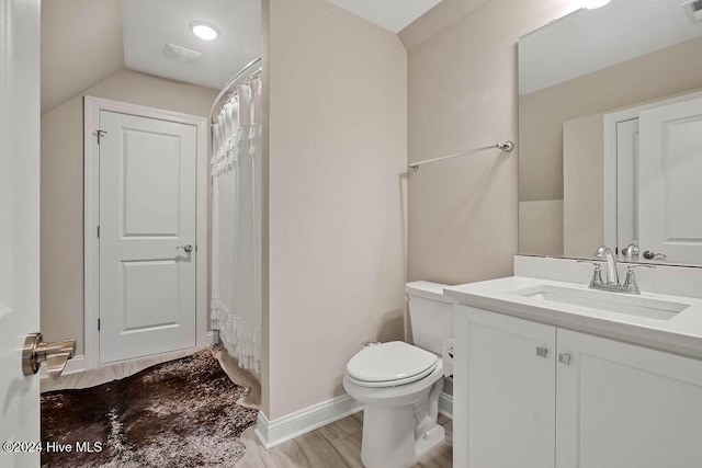 bathroom with toilet, vanity, hardwood / wood-style flooring, and vaulted ceiling