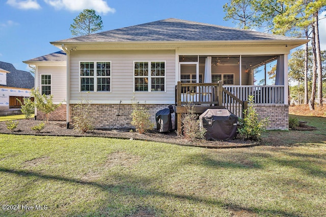 rear view of property with a lawn, a sunroom, and a wooden deck