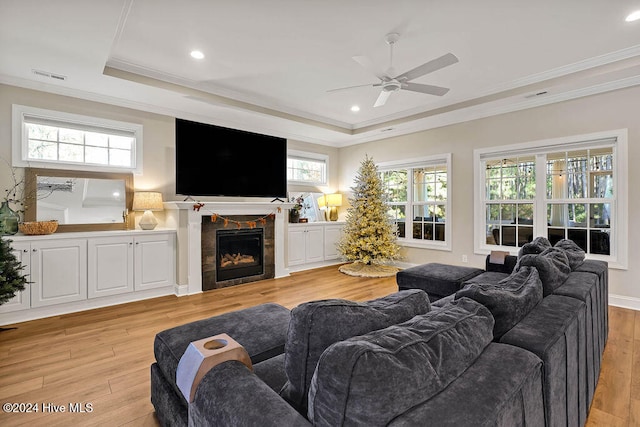 living room featuring a fireplace, light hardwood / wood-style flooring, a healthy amount of sunlight, and ornamental molding