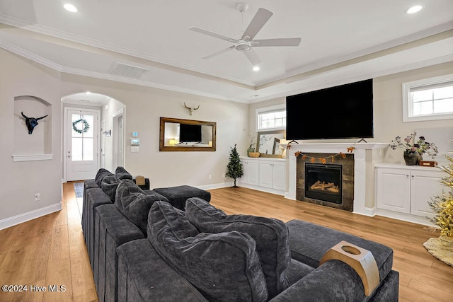 living room with ceiling fan, light wood-type flooring, crown molding, and a wealth of natural light