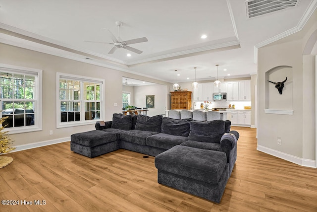 living room featuring crown molding, ceiling fan, and light wood-type flooring