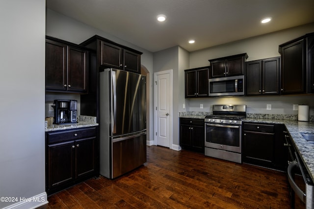 kitchen featuring light stone counters, dark wood-type flooring, and appliances with stainless steel finishes