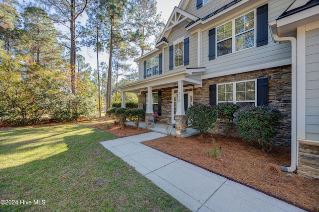 270 Hydrangea Ln, Hampstead, NC 28443 - view of exterior entry with covered porch, a yard, and stone siding