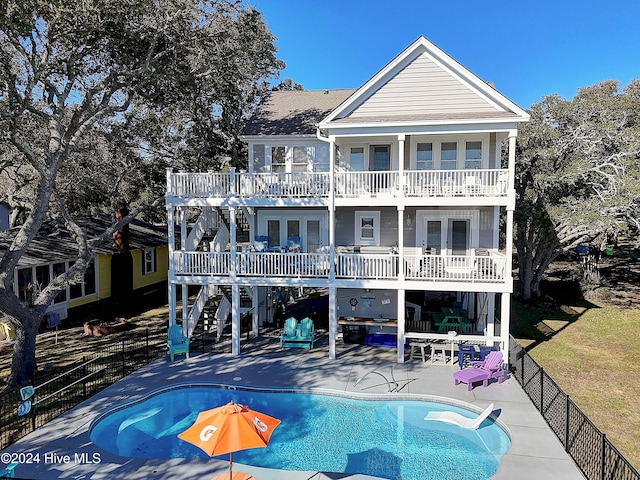 rear view of property with a fenced in pool, a balcony, a patio, and french doors