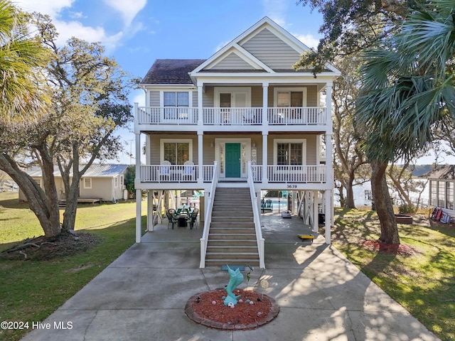 coastal home featuring a carport, covered porch, a balcony, and a front yard