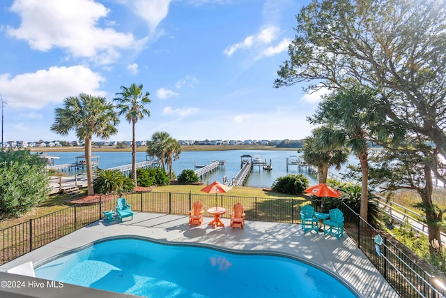 view of swimming pool featuring a patio, a water view, a dock, and a lawn