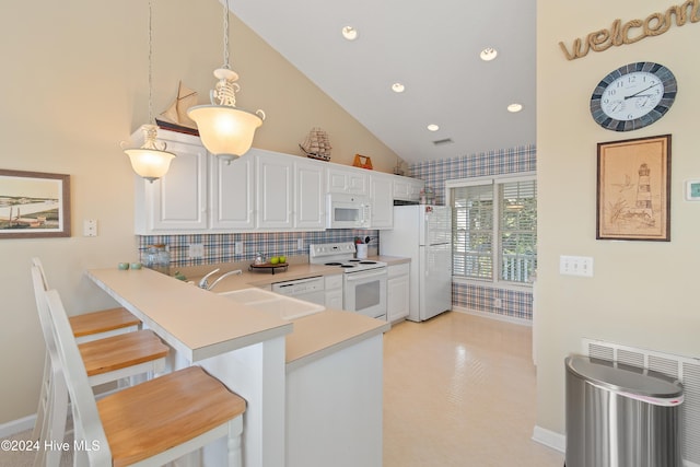 kitchen featuring white appliances, white cabinets, a kitchen breakfast bar, decorative light fixtures, and kitchen peninsula