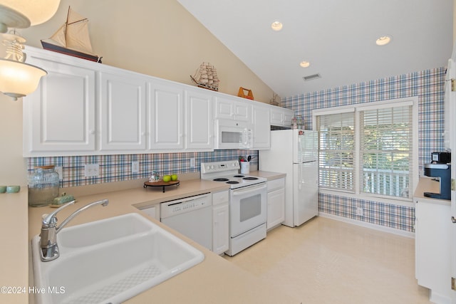 kitchen featuring white appliances, white cabinetry, vaulted ceiling, and sink