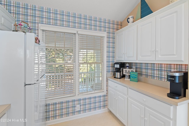 kitchen featuring white cabinets, a textured ceiling, white refrigerator, and lofted ceiling