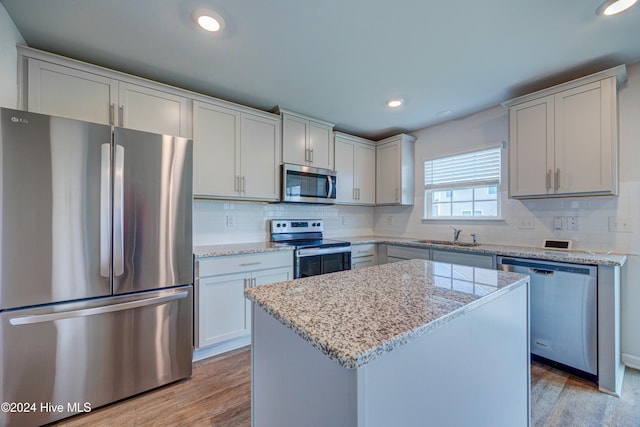 kitchen featuring backsplash, a center island, light wood-type flooring, and appliances with stainless steel finishes