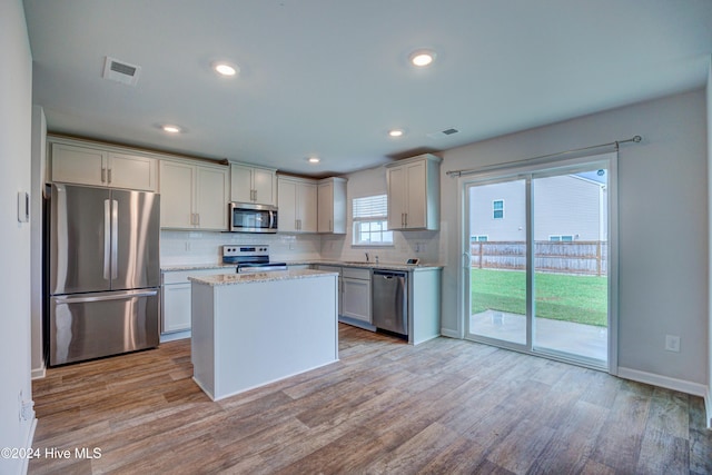 kitchen with backsplash, sink, light hardwood / wood-style flooring, and appliances with stainless steel finishes