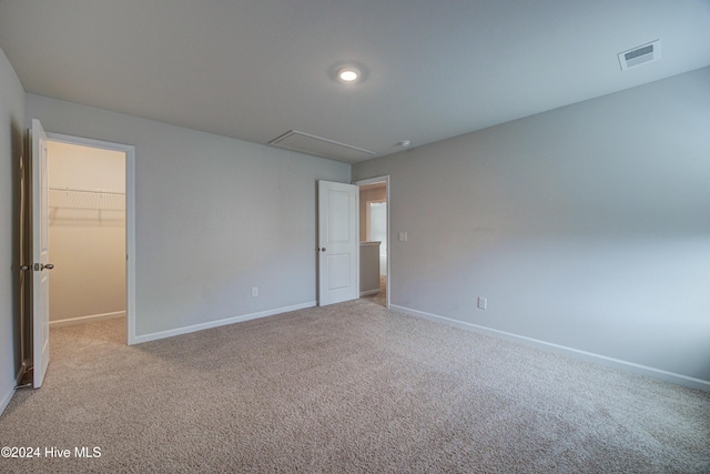 unfurnished bedroom featuring a spacious closet, a closet, and light carpet