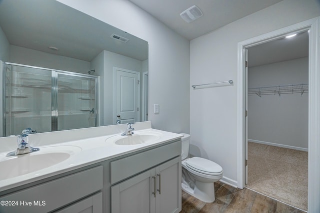 bathroom with vanity, toilet, wood-type flooring, and a shower with door