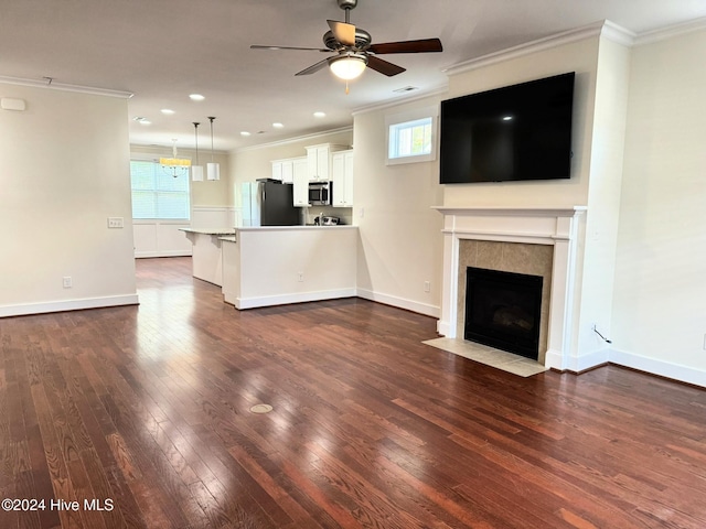 unfurnished living room featuring dark hardwood / wood-style floors, ornamental molding, ceiling fan with notable chandelier, and a tile fireplace