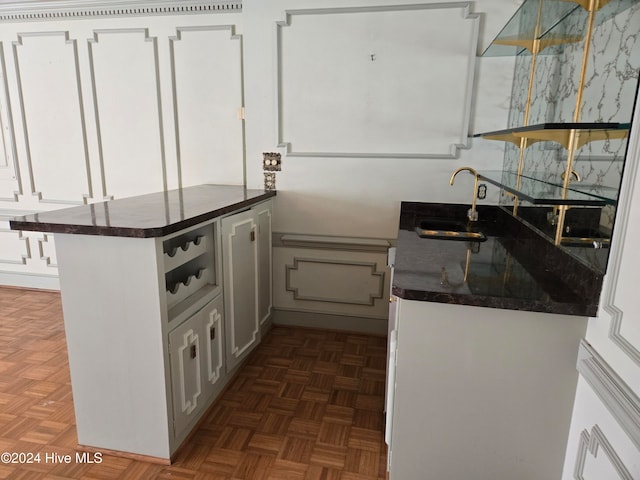 kitchen featuring white cabinets, dark parquet flooring, kitchen peninsula, and sink