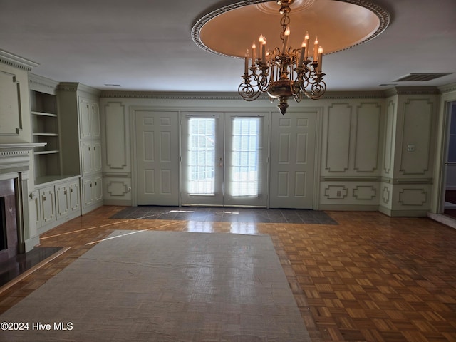 entrance foyer featuring a notable chandelier, dark parquet floors, a high end fireplace, and french doors