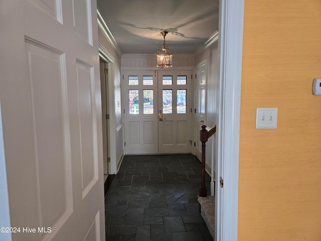 entryway with crown molding and a notable chandelier