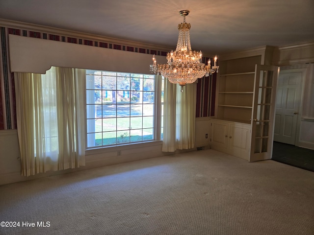 unfurnished dining area with built in features, carpet floors, crown molding, and a notable chandelier