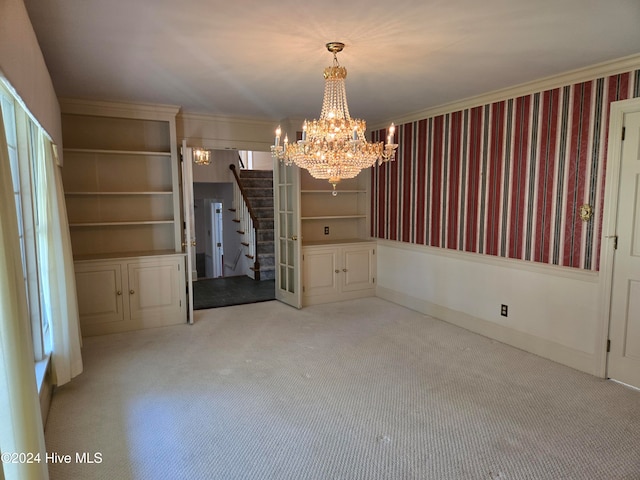 unfurnished dining area with a chandelier, light carpet, built in shelves, and crown molding