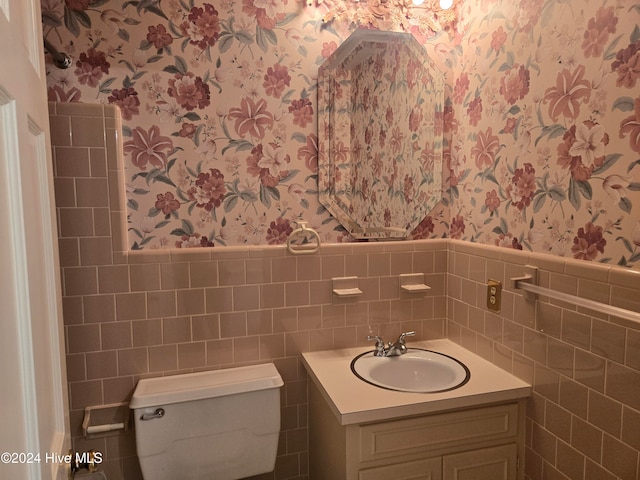 bathroom with vanity, toilet, and tile walls