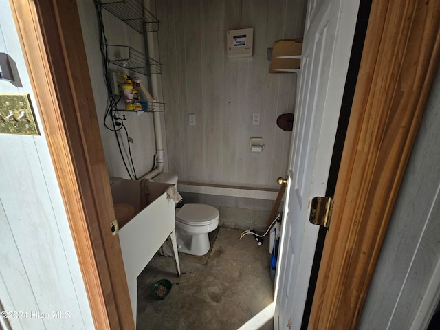 bathroom featuring vanity, concrete floors, toilet, and wood walls